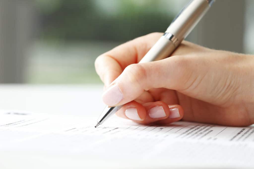 Businesswoman's hand with pen completing personal information on a form